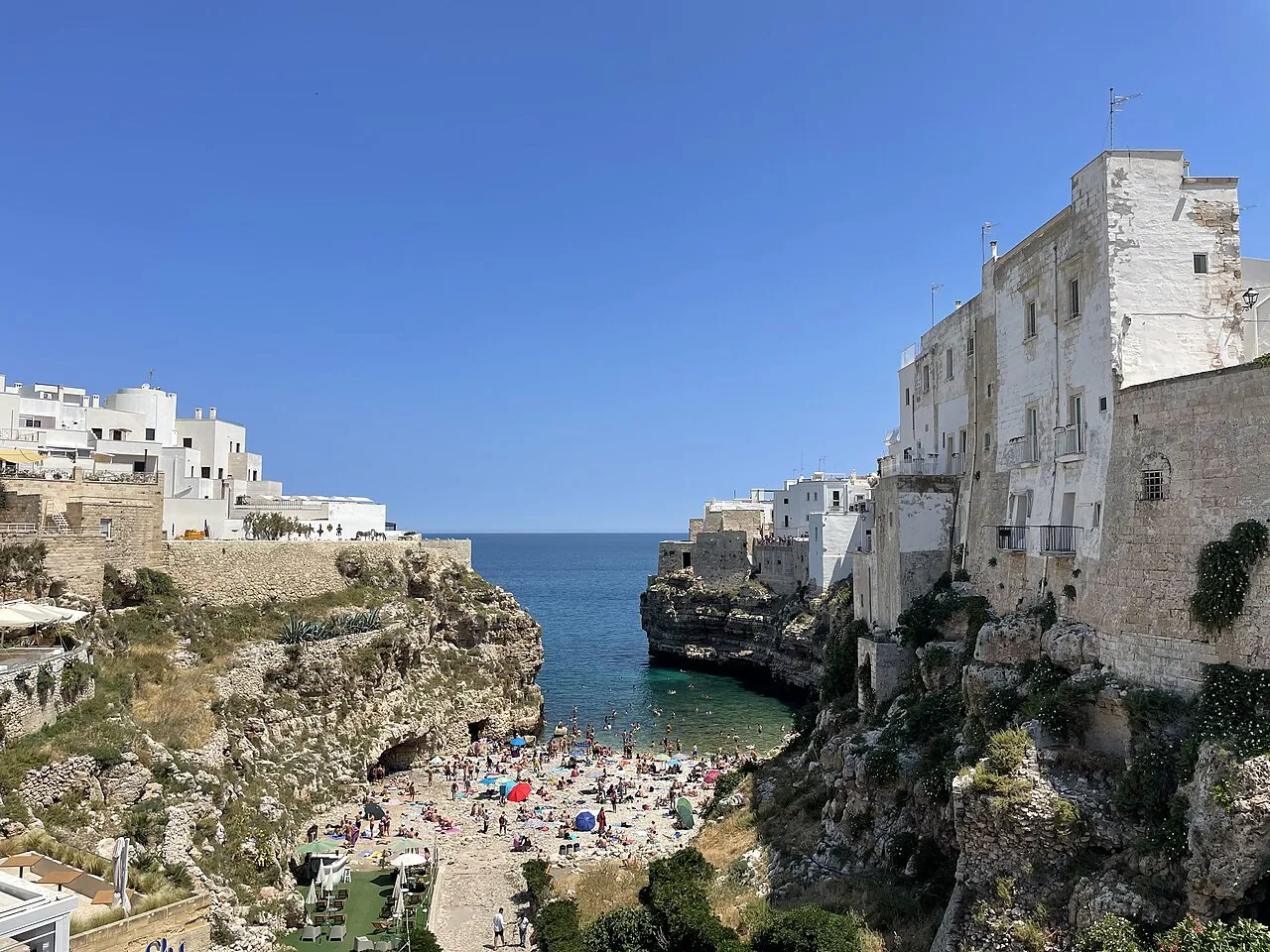 Lama Monachile’s pebble cove between limestone cliffs and white houses in Polignano a Mare