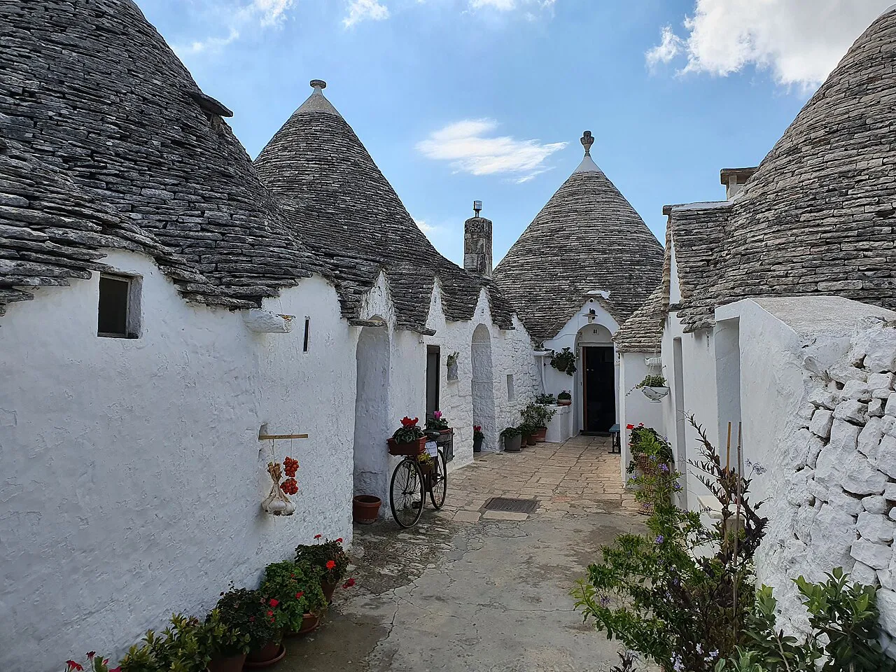 A narrow lane lined with whitewashed trulli and conical stone roofs in Alberobello