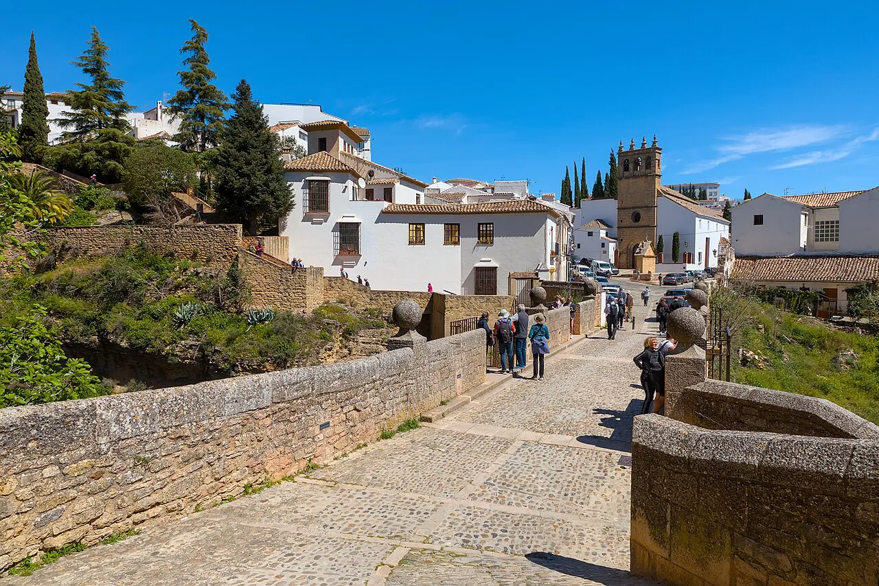 Cobbled Puente Viejo in Ronda leading to whitewashed houses and the church tower of Padre Jesús