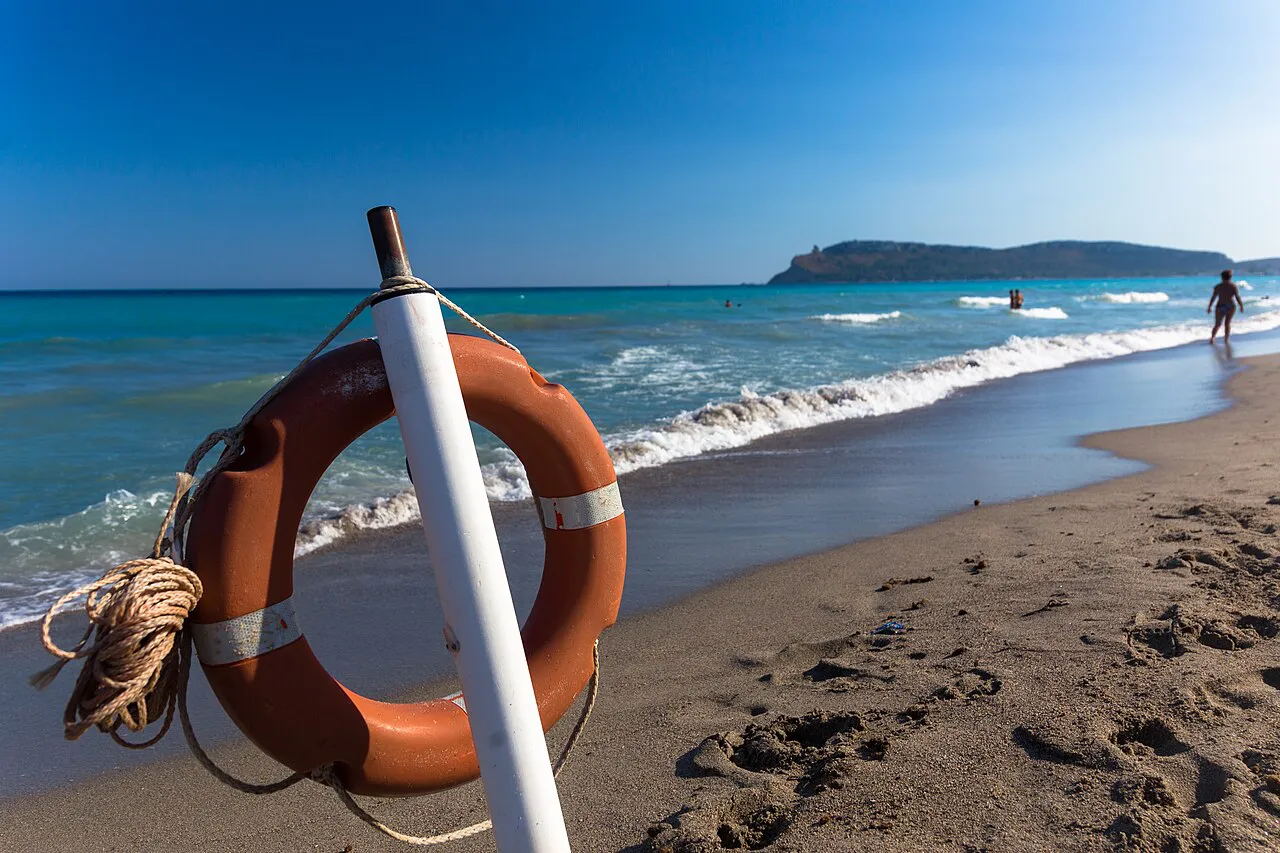 Poetto beach in Cagliari with waves rolling in and the Sella del Diavolo headland behind