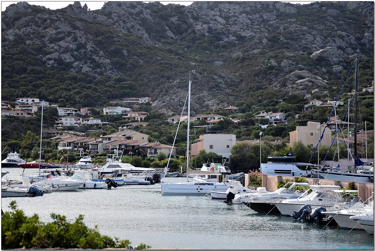 Yachts moored in the Porto Cervo marina below pastel houses and rocky granite hills