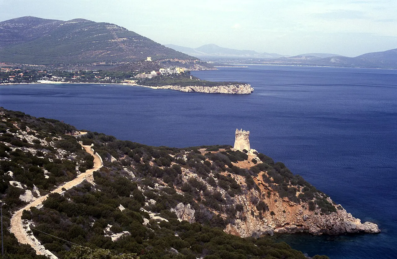 The Torre del Buru watchtower on a rocky headland above the deep blue bay of Porto Conte near Alghero