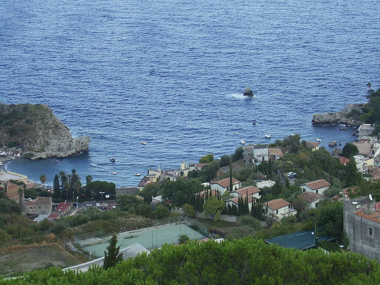 Mazzarò bay and its rocky headland seen from the hillside of Taormina above the blue sea