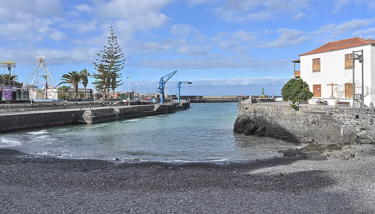 Small black-sand harbour of Puerto de la Cruz with a white historic customs house and palms, Tenerife